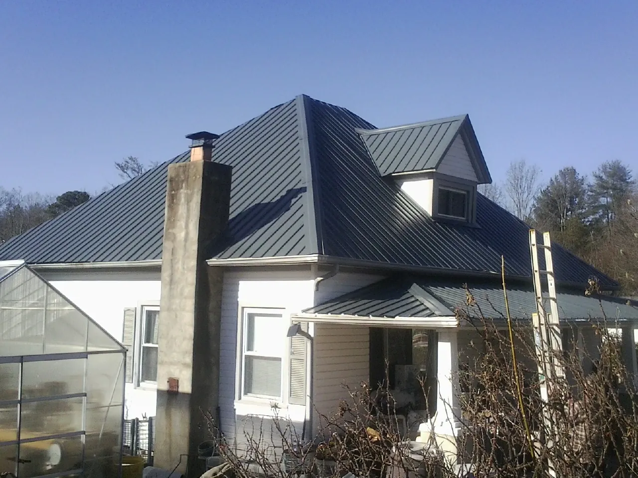Dark blue standing seam metal roof on a white farmhouse with dormer in Lagrange