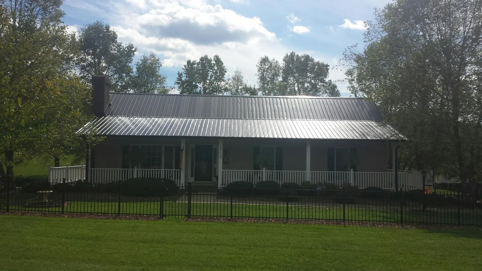 Gray metal roof on a brick ranch with a full width front porch — Gutter Guard Installation work by our crew in Lagrange