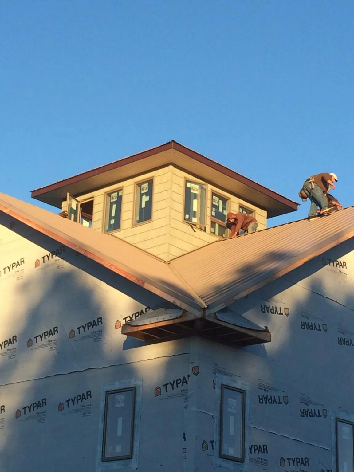 Roofers working around a rooftop cupola on a new metal roof at sunset — Roof Waterproofing in Lagrange by Roofing Brothers
